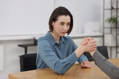 Competition concept. Businesswomen arm wrestling at table in office, closeup