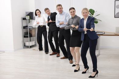 Photo of Competition concept. Group of businesspeople pulling rope in office