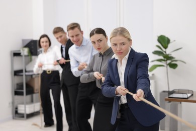 Competition concept. Group of businesspeople pulling rope in office