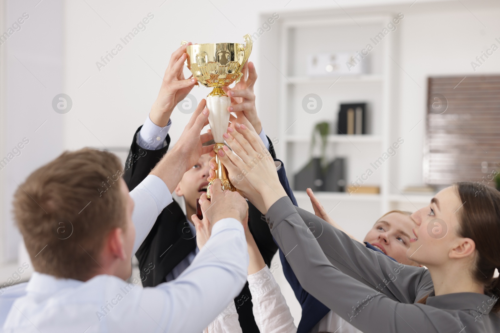 Photo of Competition concept. Group of businesspeople with golden trophy in office