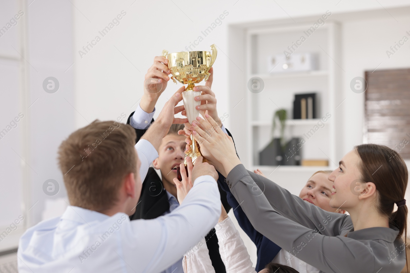 Photo of Competition concept. Group of businesspeople with golden trophy in office