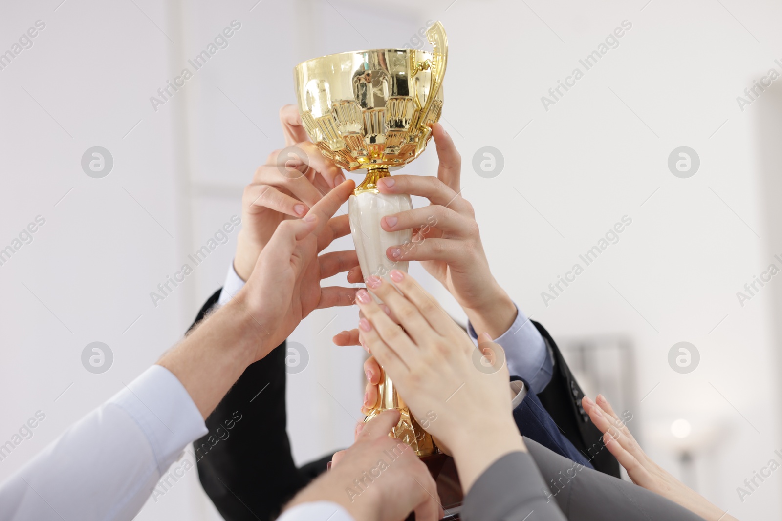 Photo of Competition concept. Group of businesspeople with golden trophy in office, closeup