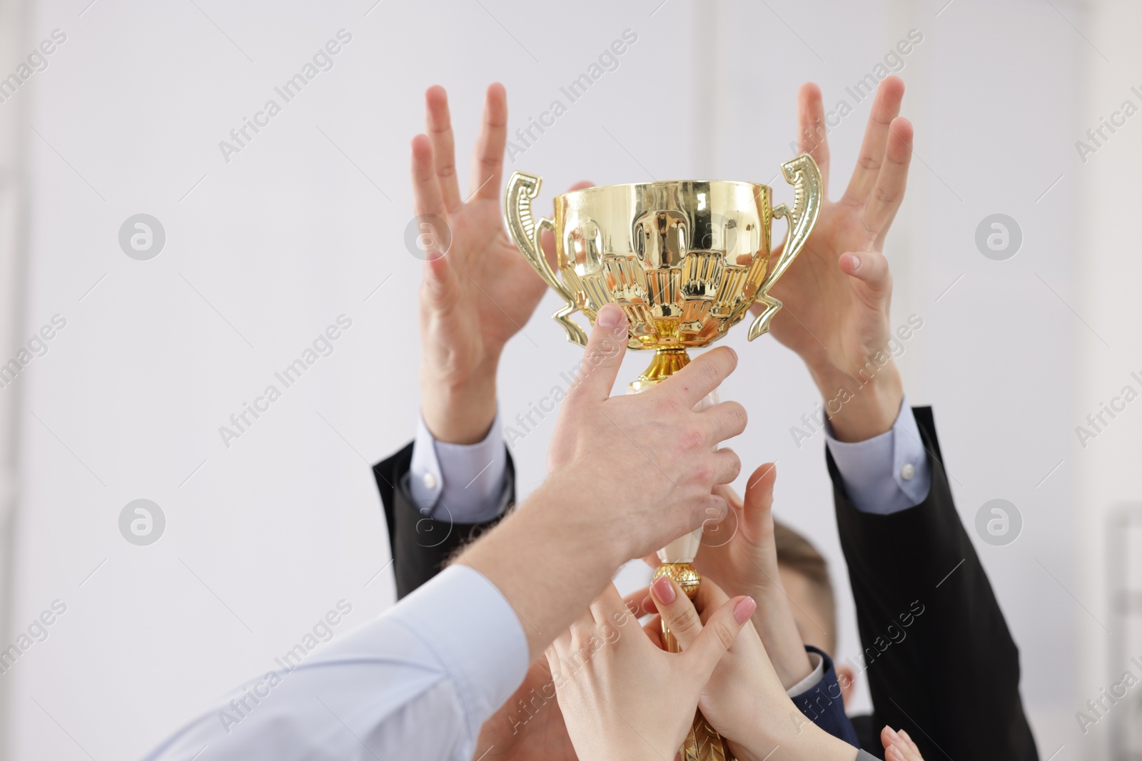 Photo of Competition concept. Group of businesspeople with golden trophy in office, closeup