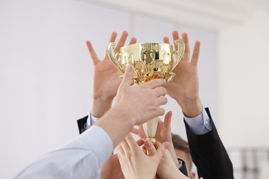 Competition concept. Group of businesspeople with golden trophy in office, closeup