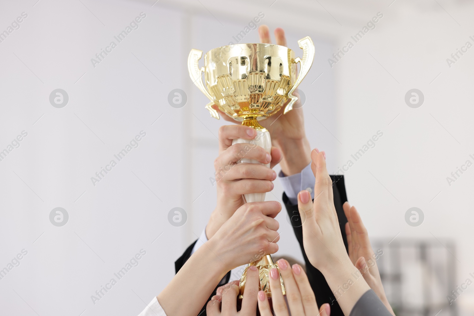 Photo of Competition concept. Group of businesspeople with golden trophy in office, closeup. Space for text