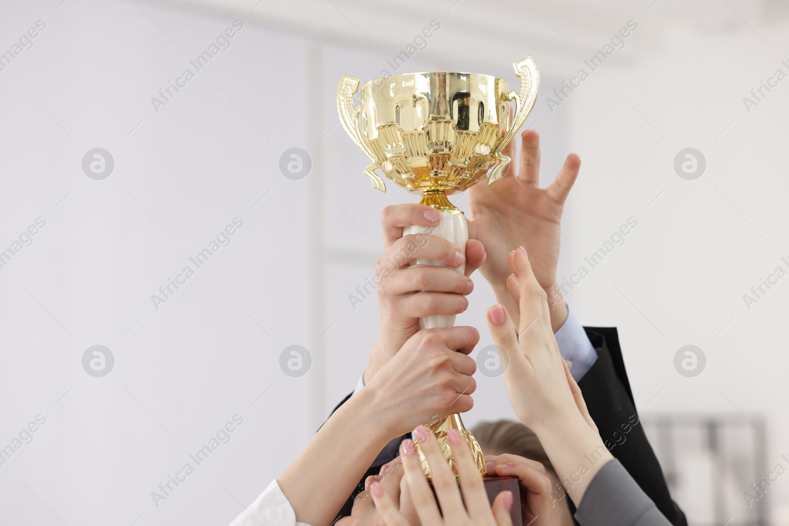 Photo of Competition concept. Group of businesspeople with golden trophy in office, closeup. Space for text