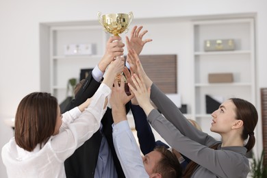 Competition concept. Group of businesspeople with golden trophy in office