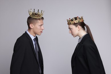 Photo of Business competition. Colleagues in golden crowns looking at each other on grey background