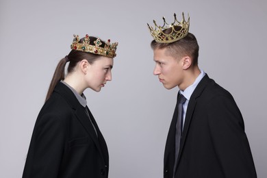 Photo of Business competition. Colleagues in golden crowns looking at each other on grey background