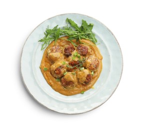 Photo of Delicious meatballs with gravy cream sauce, herbs and arugula isolated on white, top view