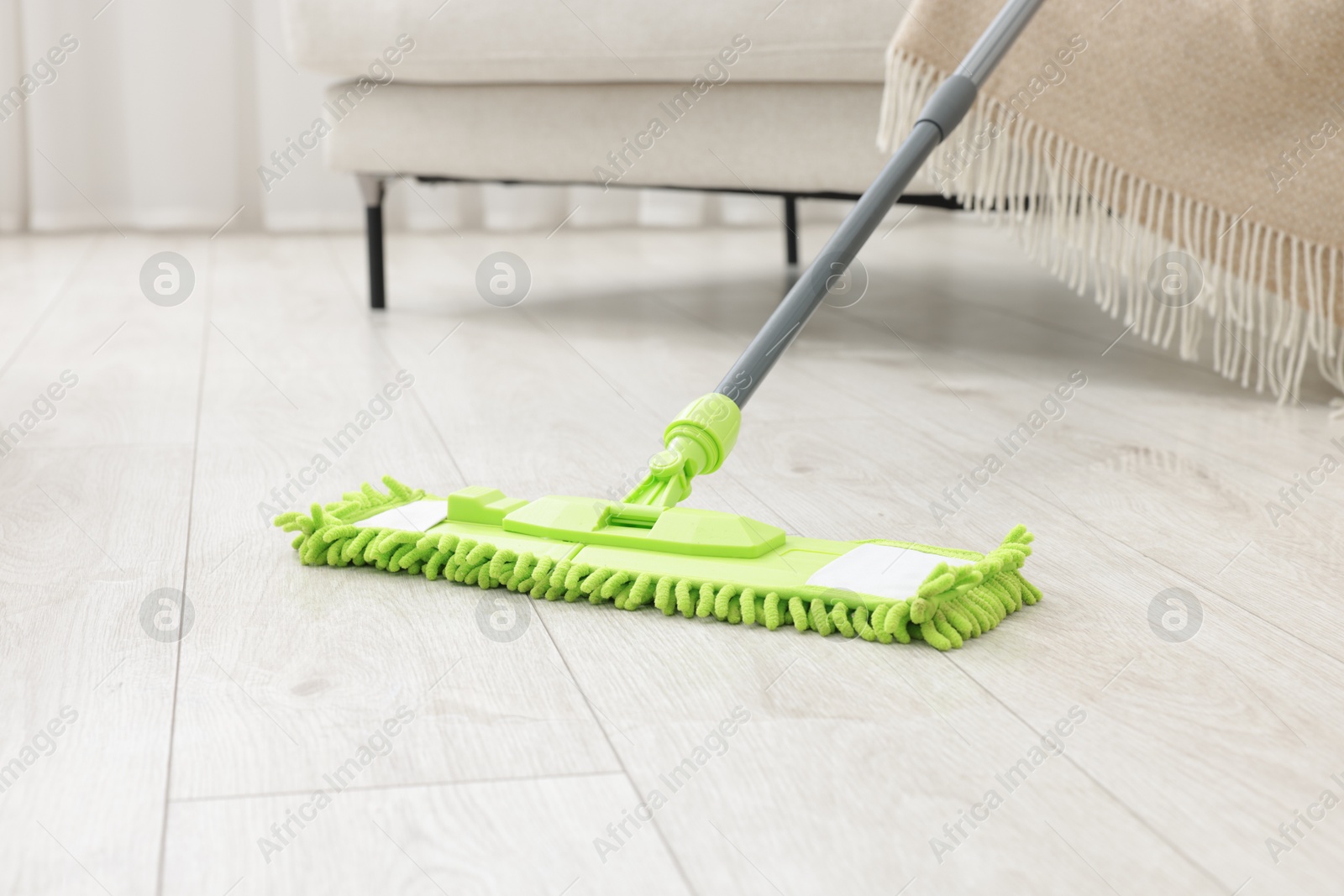 Photo of Microfiber mop on floor near sofa indoors