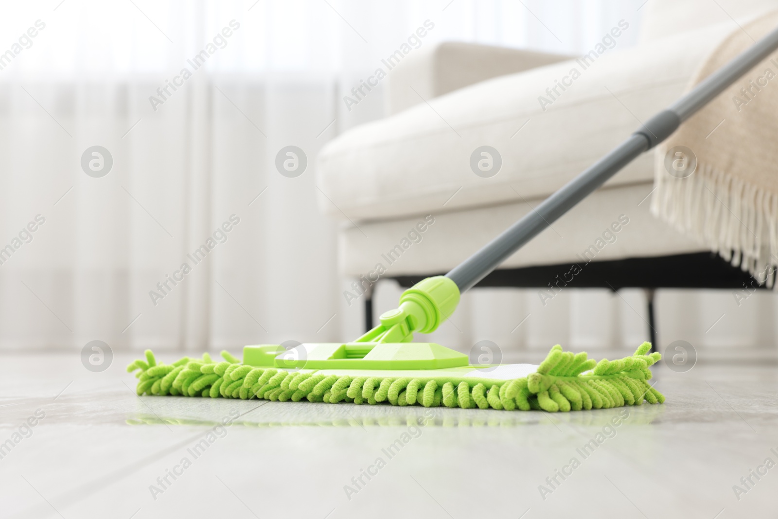 Photo of Microfiber mop on floor near sofa indoors