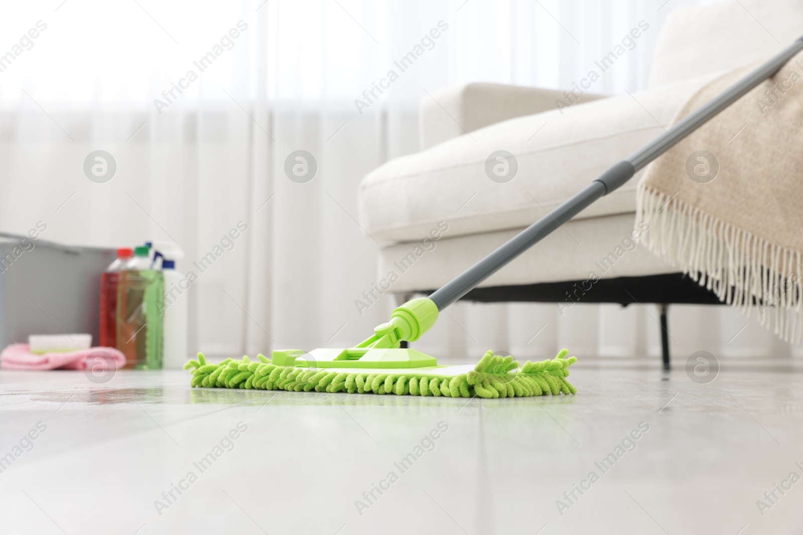 Photo of Microfiber mop on floor near sofa indoors