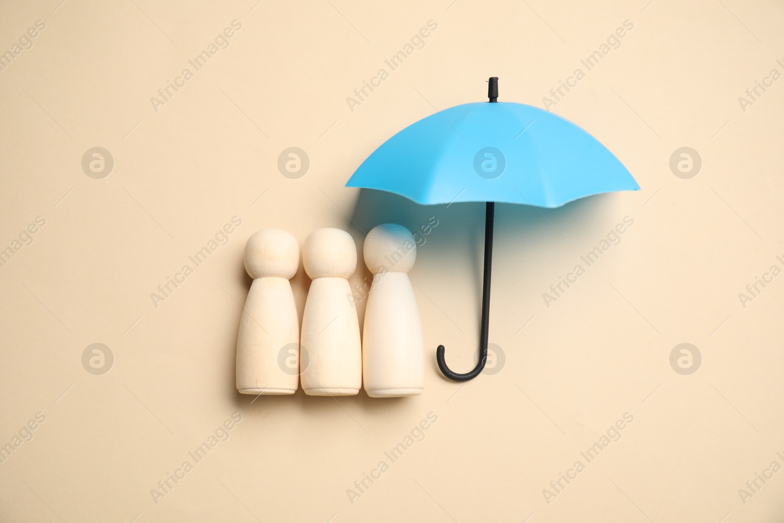 Photo of Human figures under umbrella on beige background, top view. Insurance concept