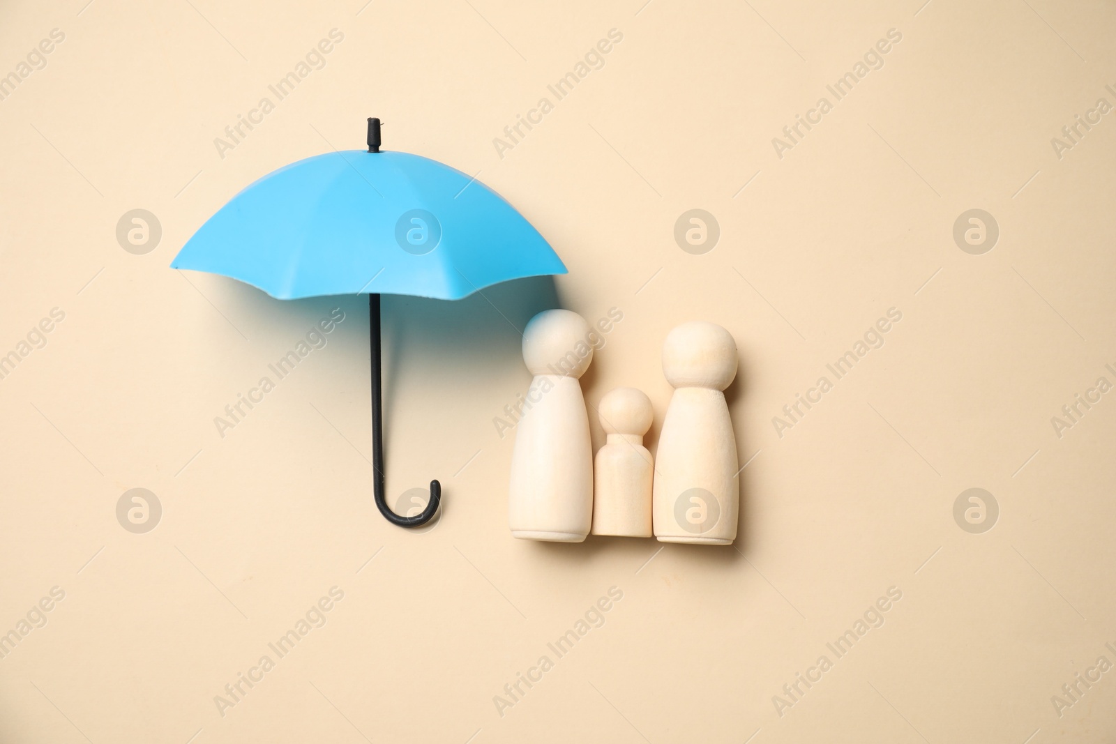 Photo of Human figures under umbrella on beige background, top view. Insurance concept