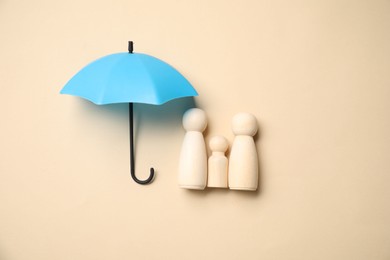 Photo of Human figures under umbrella on beige background, top view. Insurance concept