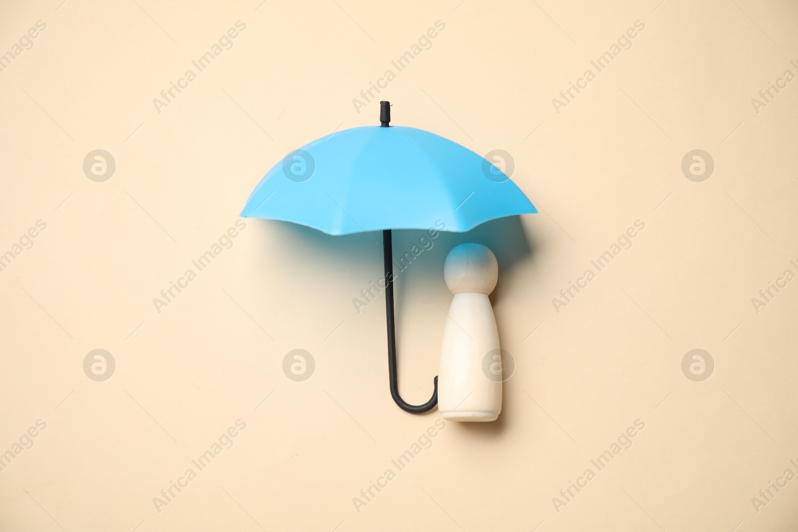 Photo of Human figure under umbrella on beige background, top view. Insurance concept