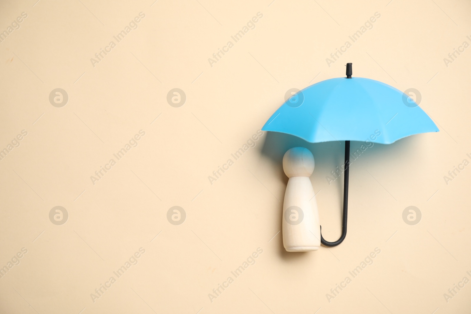 Photo of Human figure under umbrella on beige background, top view with space for text. Insurance concept