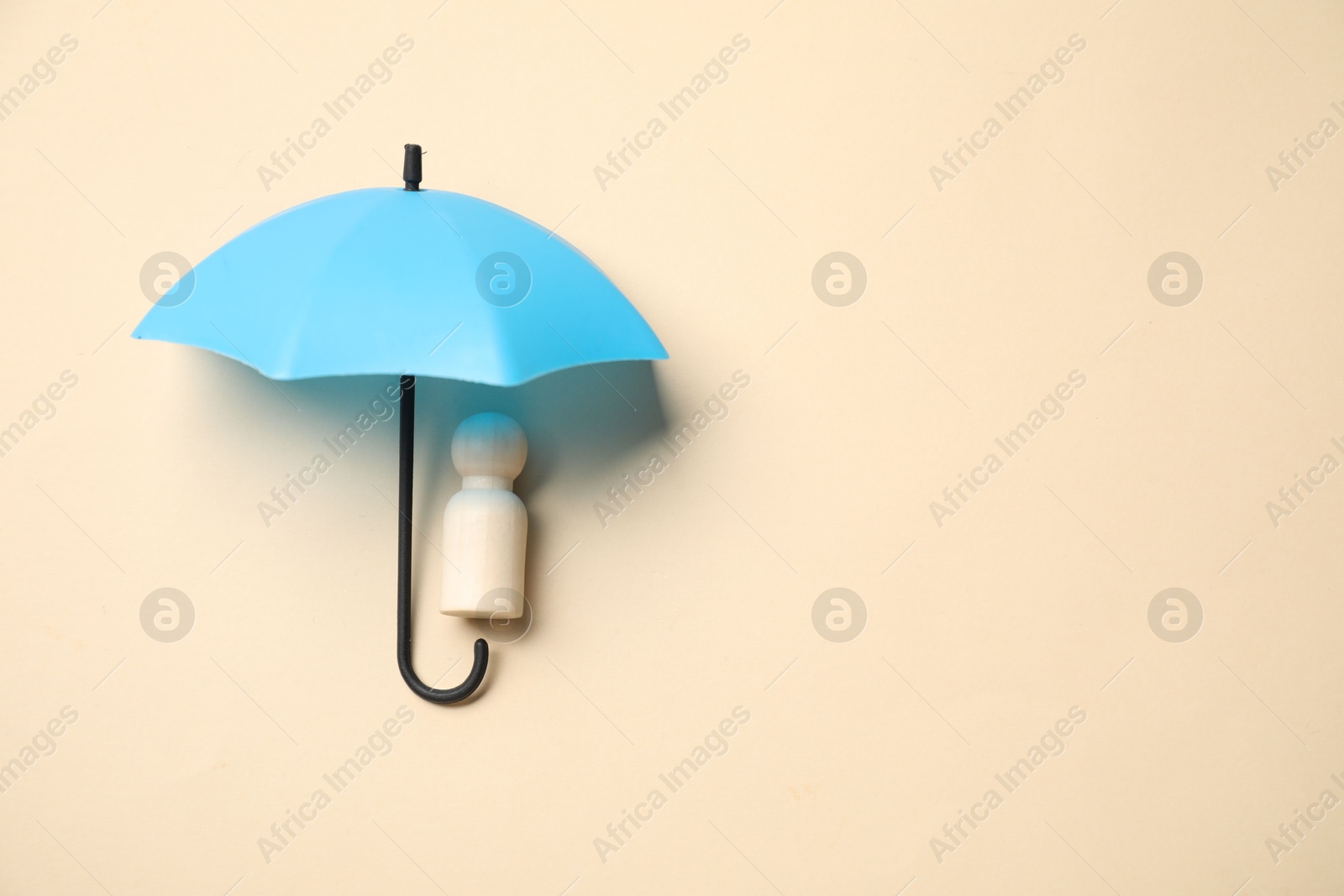 Photo of Human figure under umbrella on beige background, top view with space for text. Insurance concept