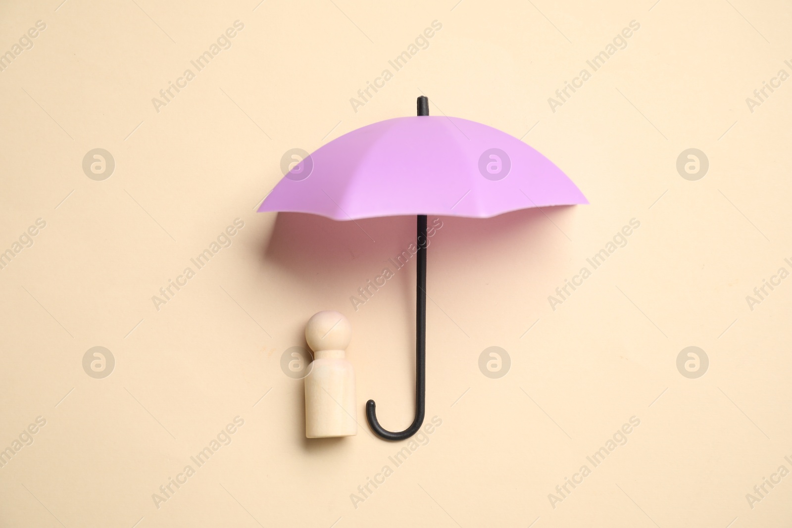 Photo of Human figure under umbrella on beige background, top view. Insurance concept