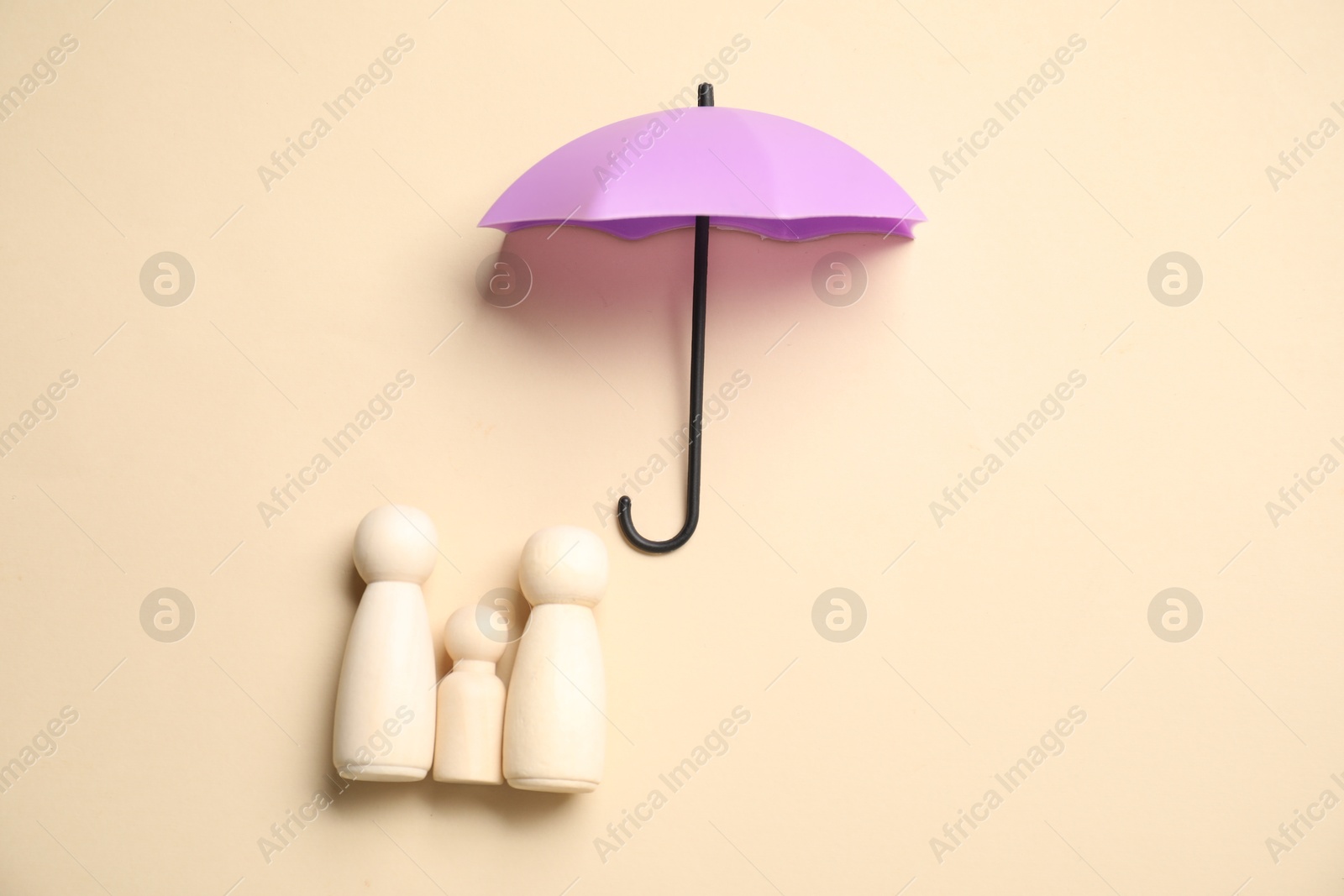 Photo of Human figures under umbrella on beige background, top view. Insurance concept