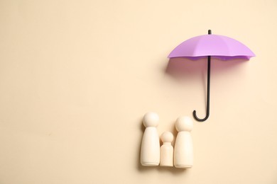 Photo of Human figures under umbrella on beige background, top view with space for text. Insurance concept