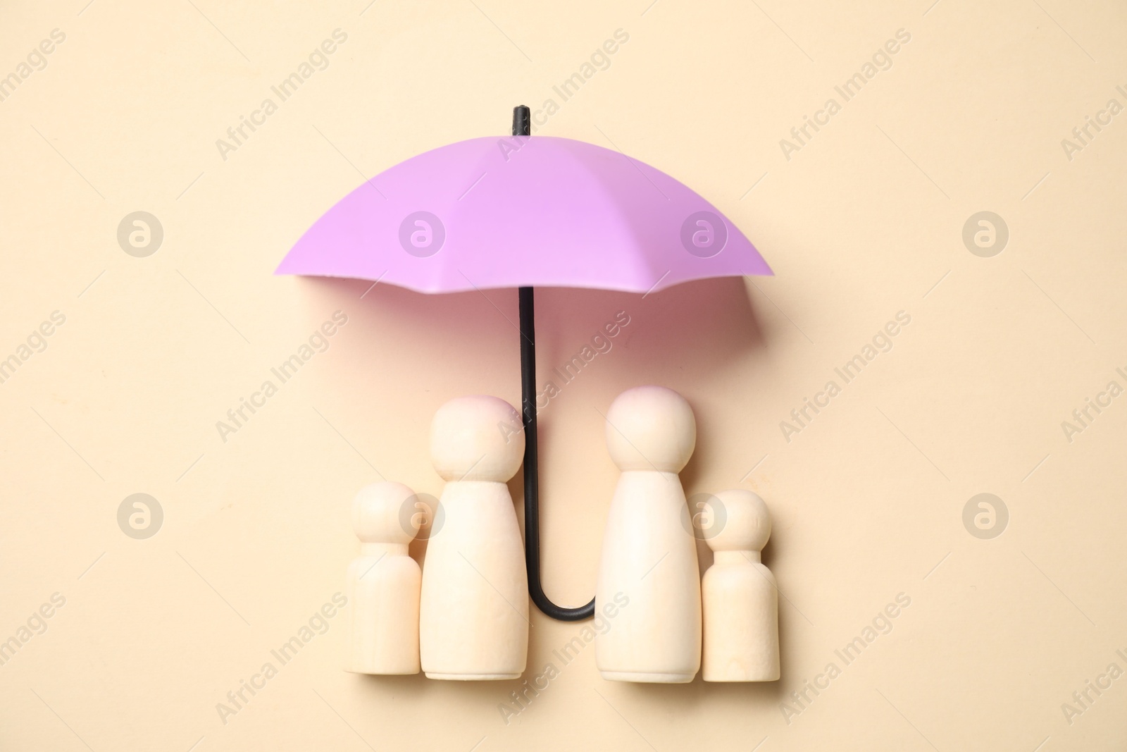 Photo of Human figures under umbrella on beige background, top view. Insurance concept