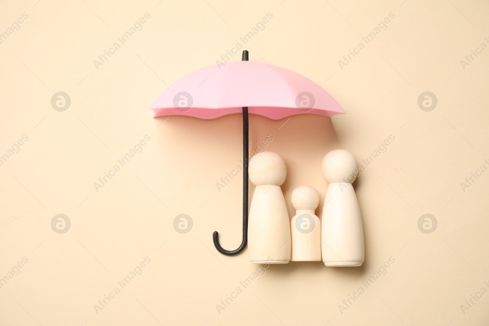 Photo of Human figures under umbrella on beige background, top view. Insurance concept