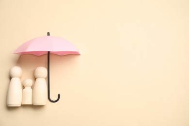 Photo of Human figures under umbrella on beige background, top view with space for text. Insurance concept