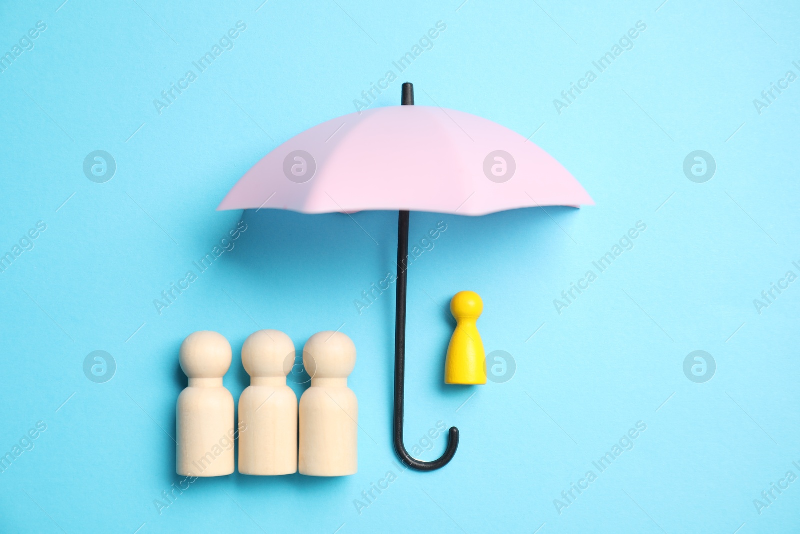 Photo of Human figures under umbrella on light blue background, top view. Insurance concept