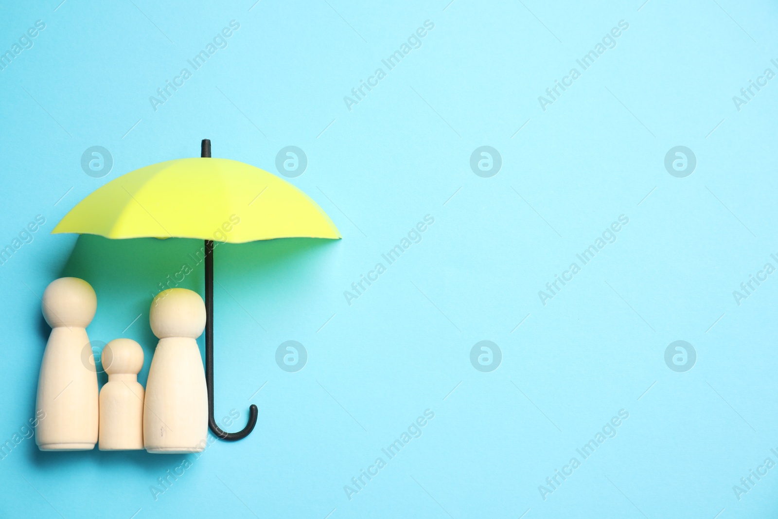 Photo of Human figures under umbrella on light blue background, top view with space for text. Insurance concept