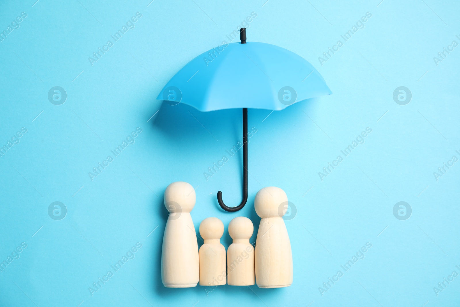 Photo of Human figures under umbrella on light blue background, top view. Insurance concept