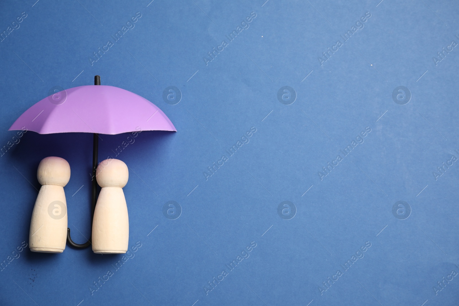 Photo of Human figures under umbrella on blue background, top view with space for text. Insurance concept