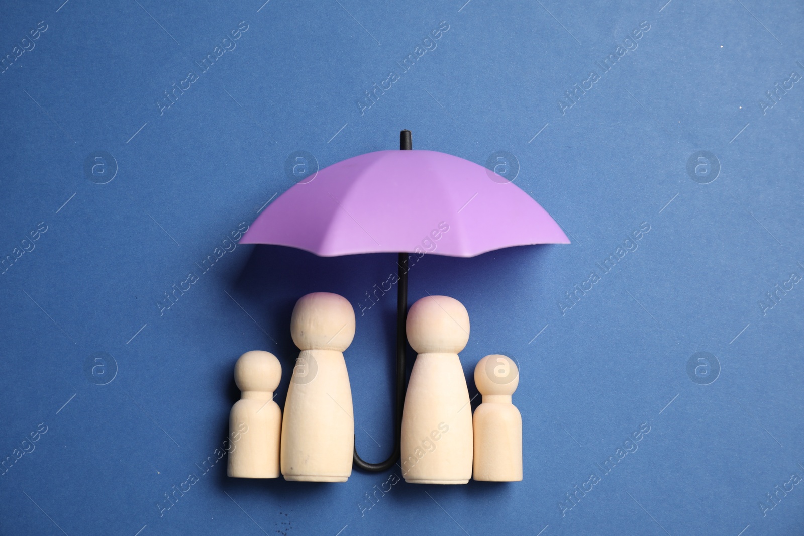 Photo of Human figures under umbrella on blue background, top view. Insurance concept