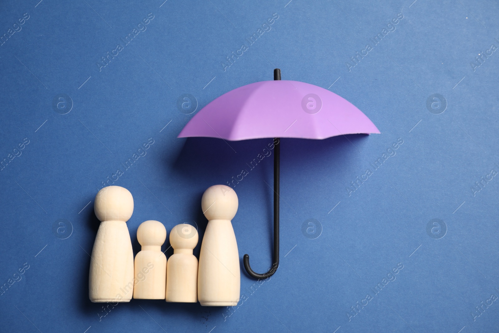 Photo of Human figures under umbrella on blue background, top view. Insurance concept