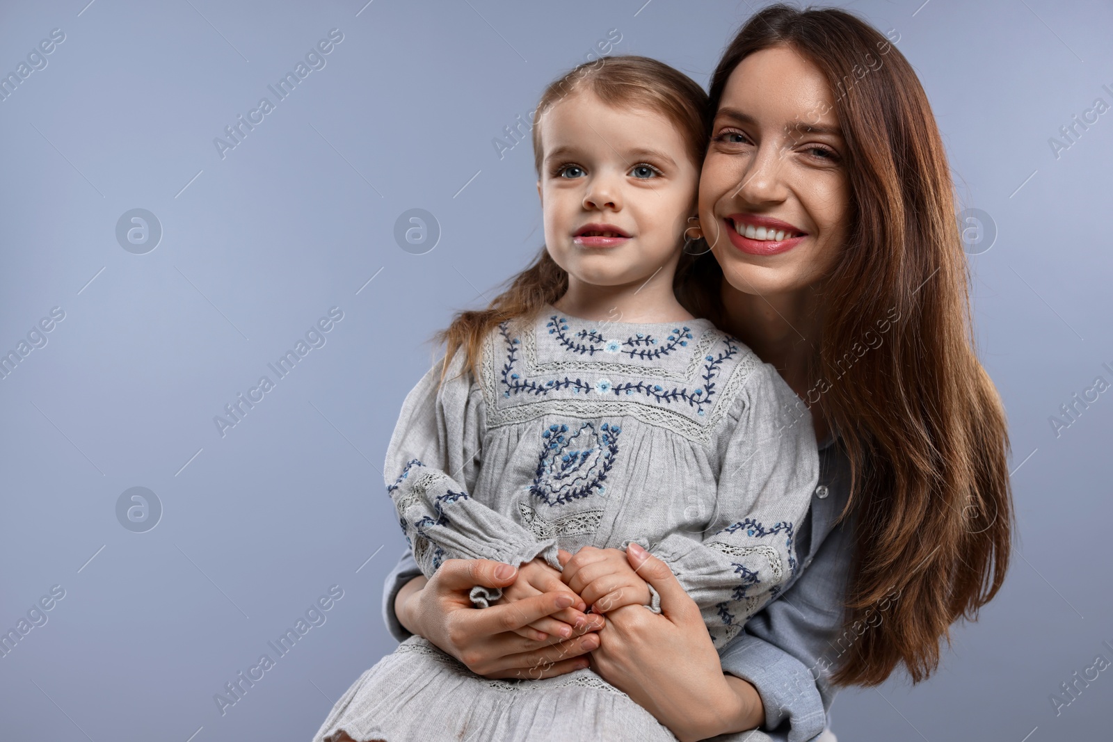 Photo of Portrait of happy mother with her cute little daughter on grey background