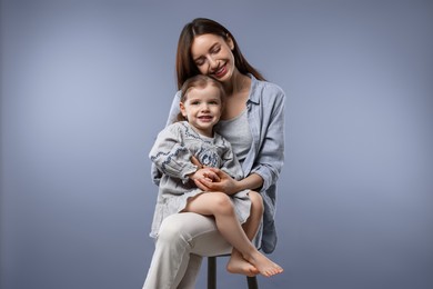 Happy mother with her cute little daughter on grey background