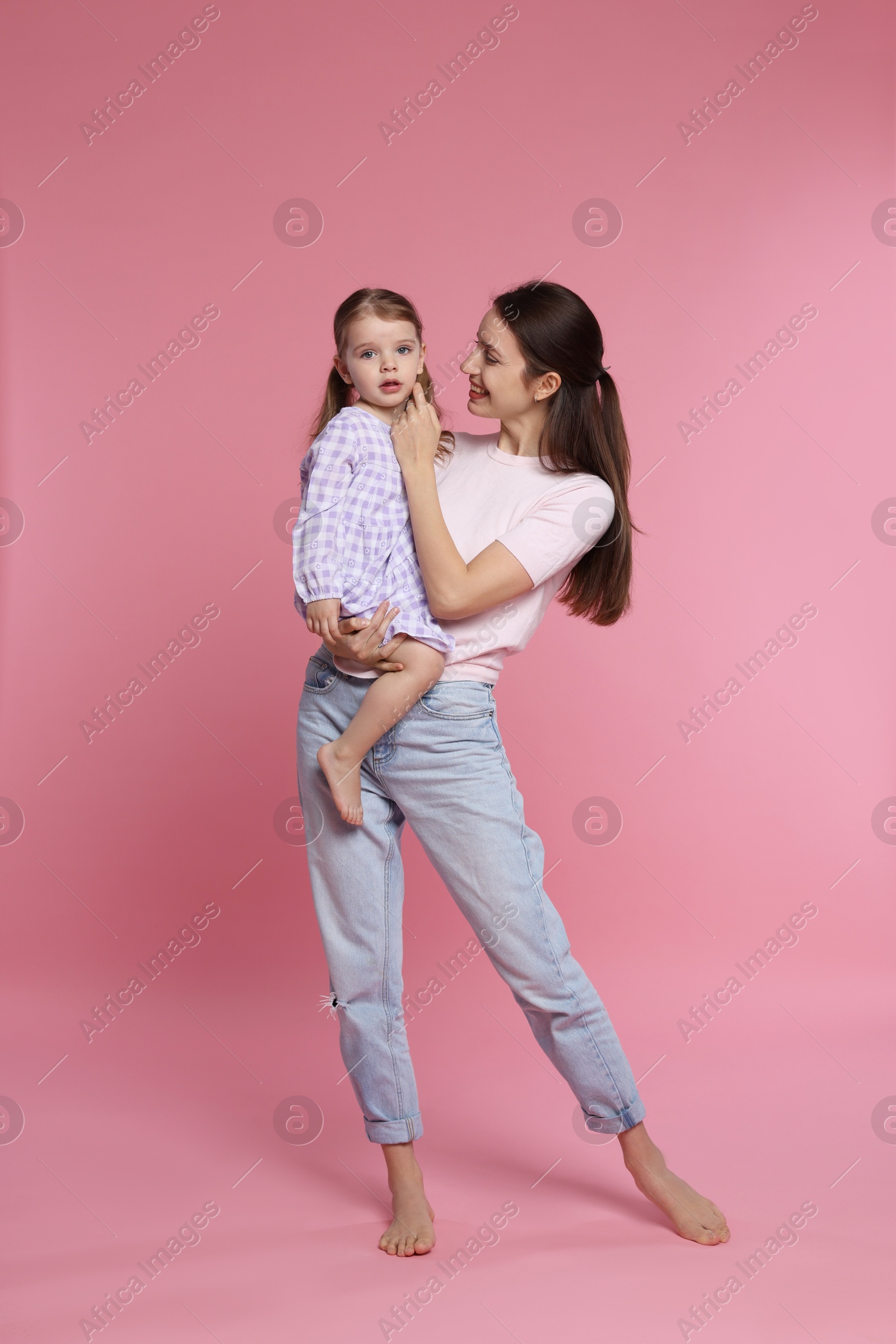 Photo of Happy mother with her cute little daughter on pink background