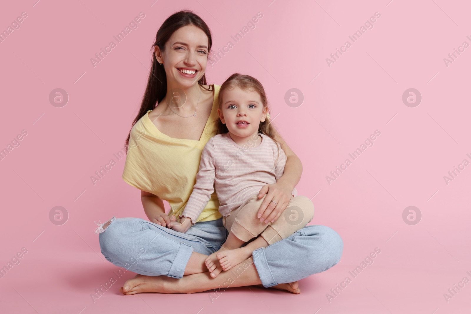 Photo of Happy mother with her cute little daughter on pink background. Space for text