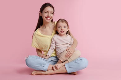 Happy mother with her cute little daughter on pink background. Space for text