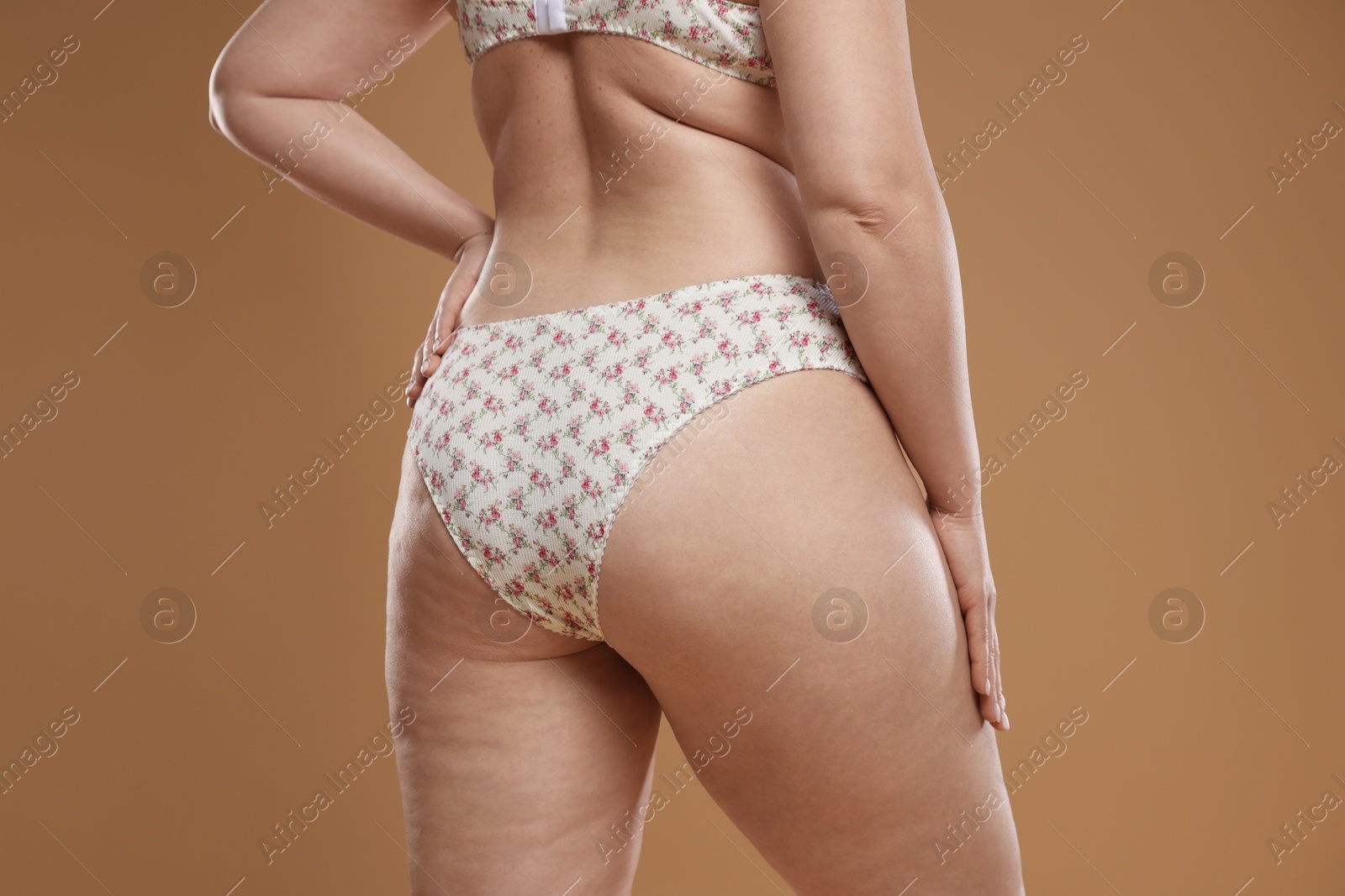 Photo of Woman with cellulite on dark beige background, closeup