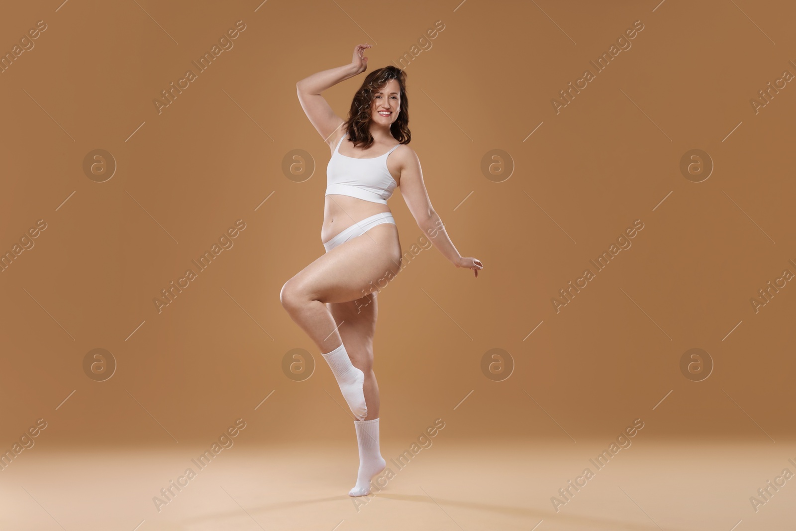 Photo of Beautiful woman in underwear on dark beige background. Cellulite problem