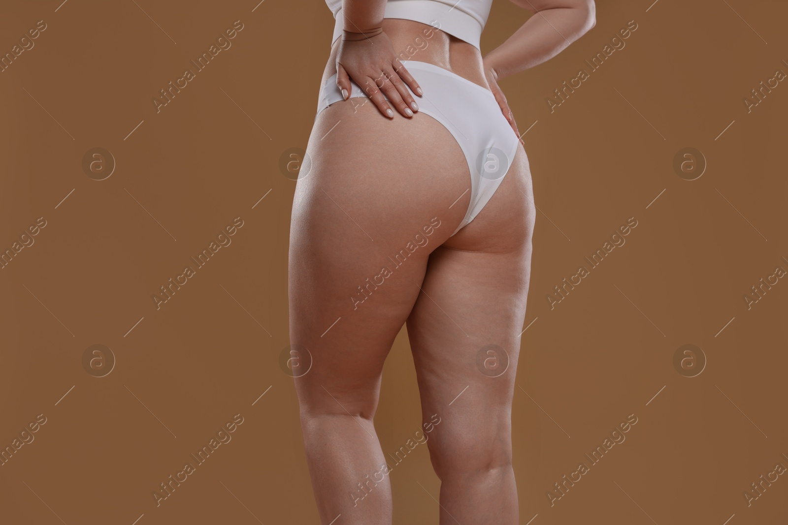 Photo of Woman with cellulite on light brown background, closeup