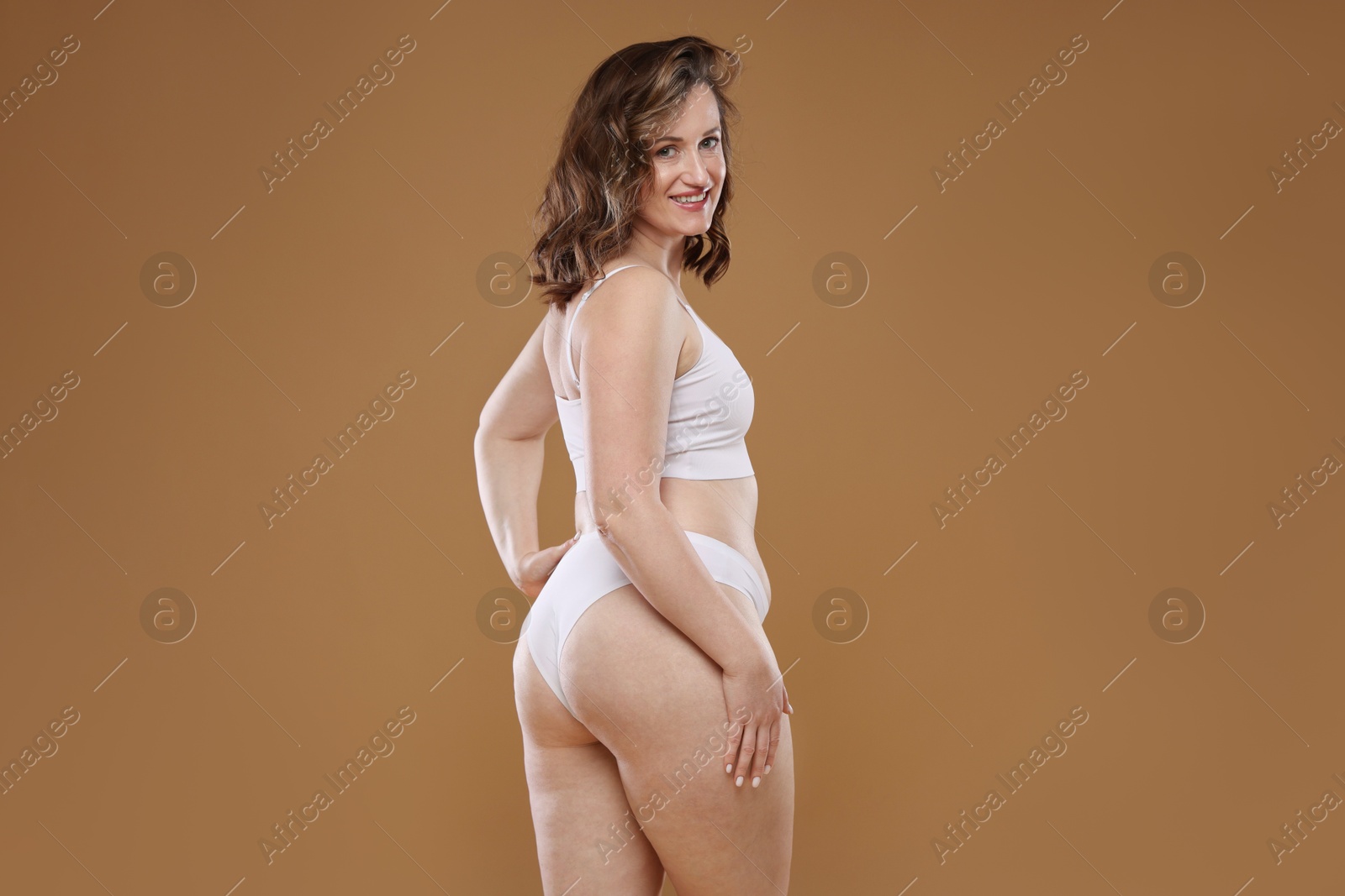 Photo of Beautiful woman in underwear on light brown background, space for text. Cellulite problem