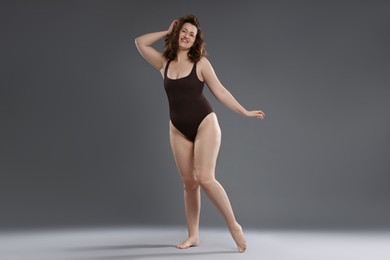 Photo of Beautiful woman in bodysuit on dark grey background. Cellulite problem