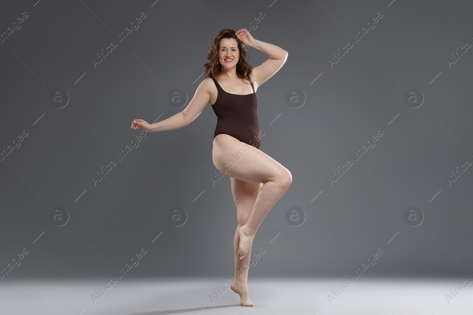 Photo of Beautiful woman in bodysuit on dark grey background. Cellulite problem