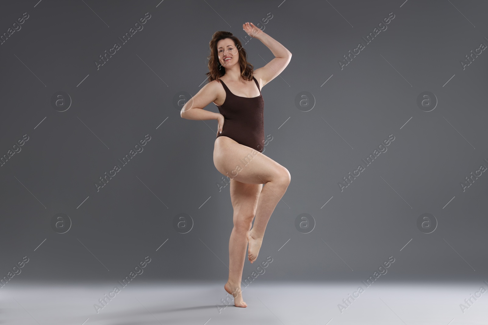 Photo of Beautiful woman in bodysuit on dark grey background. Cellulite problem