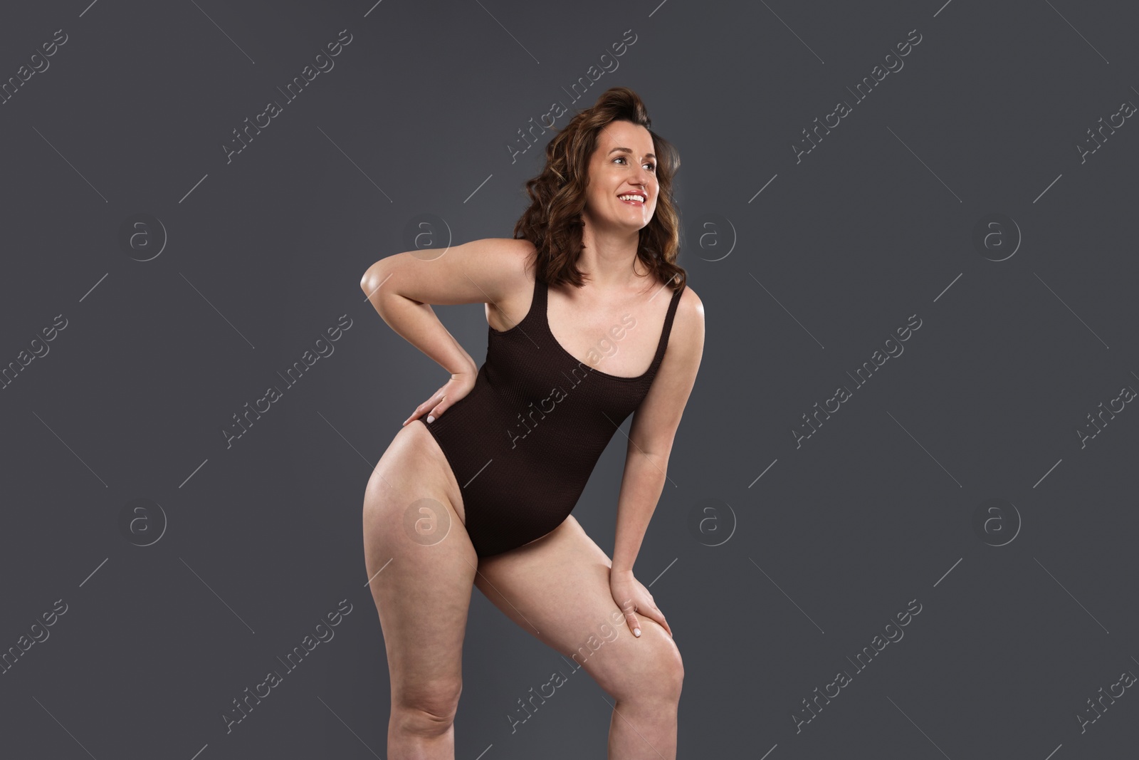 Photo of Beautiful woman in bodysuit on dark grey background. Cellulite problem