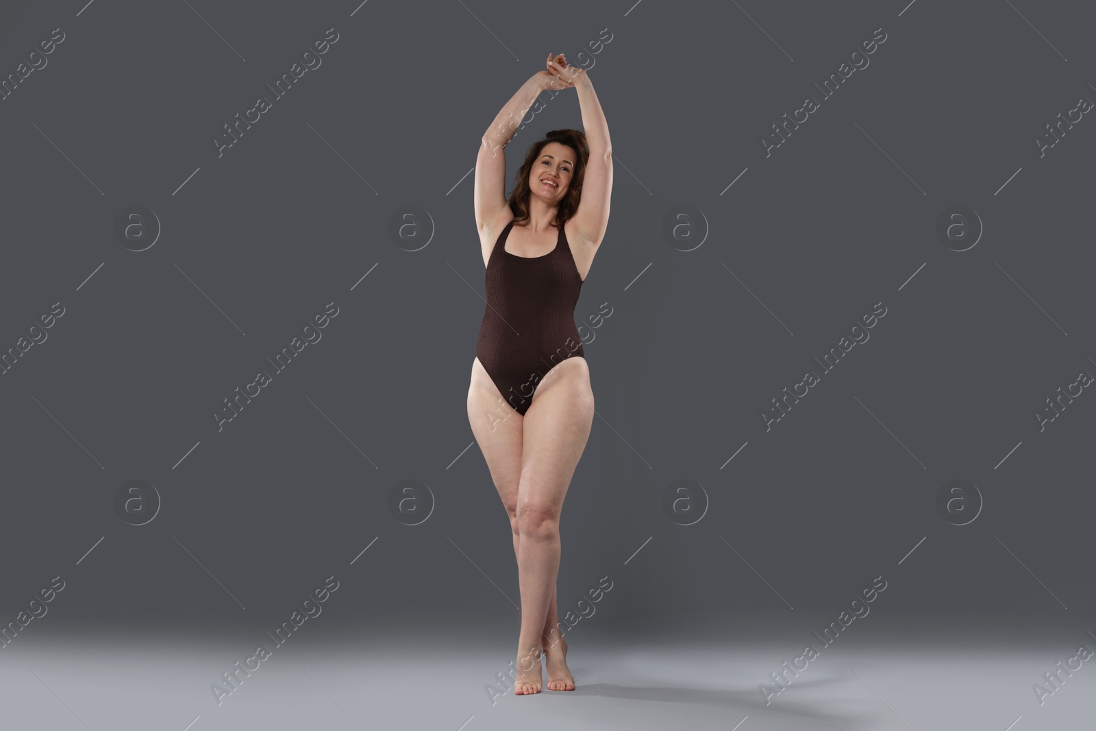 Photo of Beautiful woman in bodysuit on dark grey background. Cellulite problem