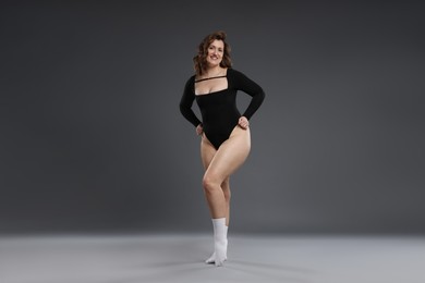 Photo of Beautiful woman in bodysuit on dark grey background. Cellulite problem